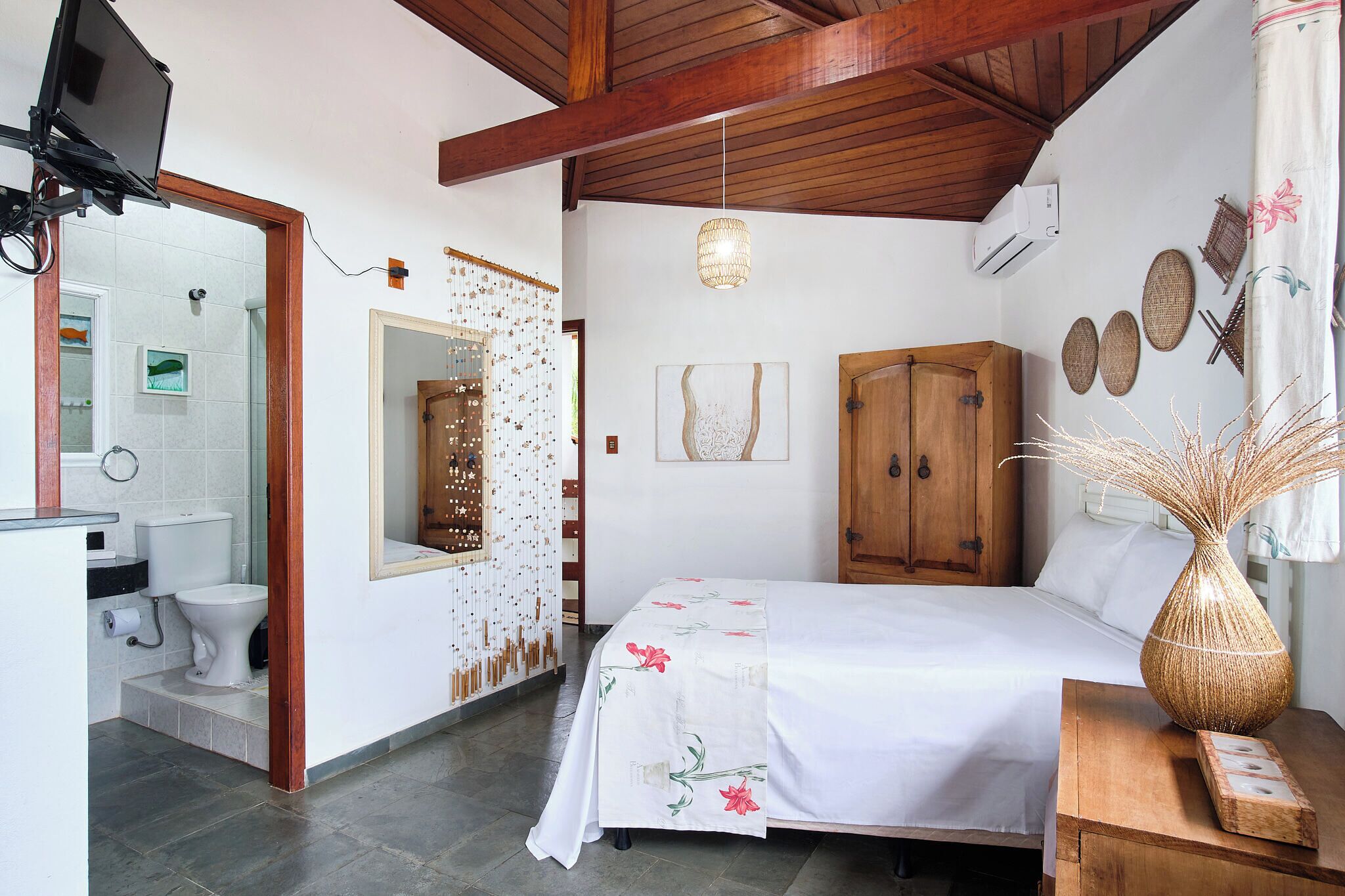 Une chambre à coucher comprenant un lit, une armoire en bois et une salle de bain avec des toilettes et un lavabo.