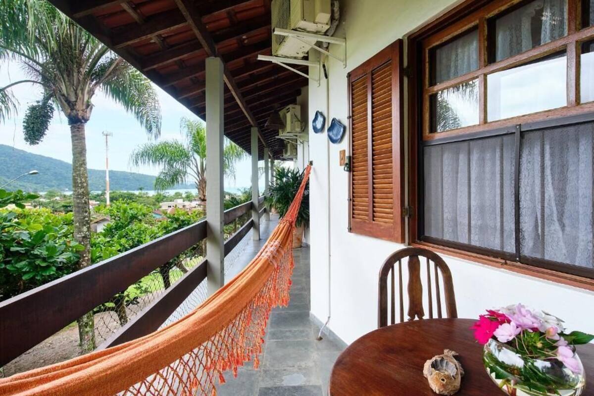 Een balkon met houten spijlen, een hangmat, een tafel met stoelen en een raam met luiken.