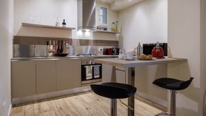 Una cocina moderna con electrodomésticos de acero inoxidable, una encimera de madera y dos taburetes negros.