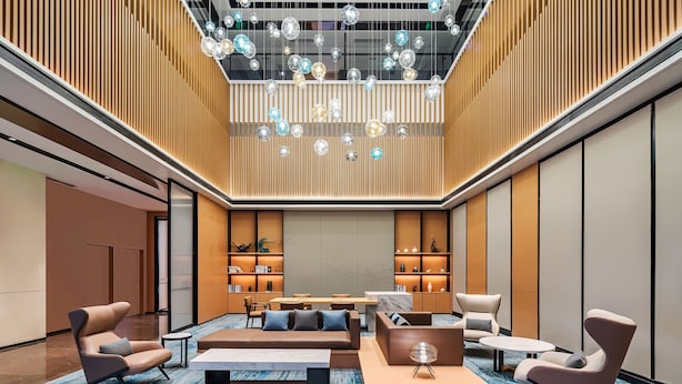 A modern lobby with seating areas, a central table, and decorative lighting.