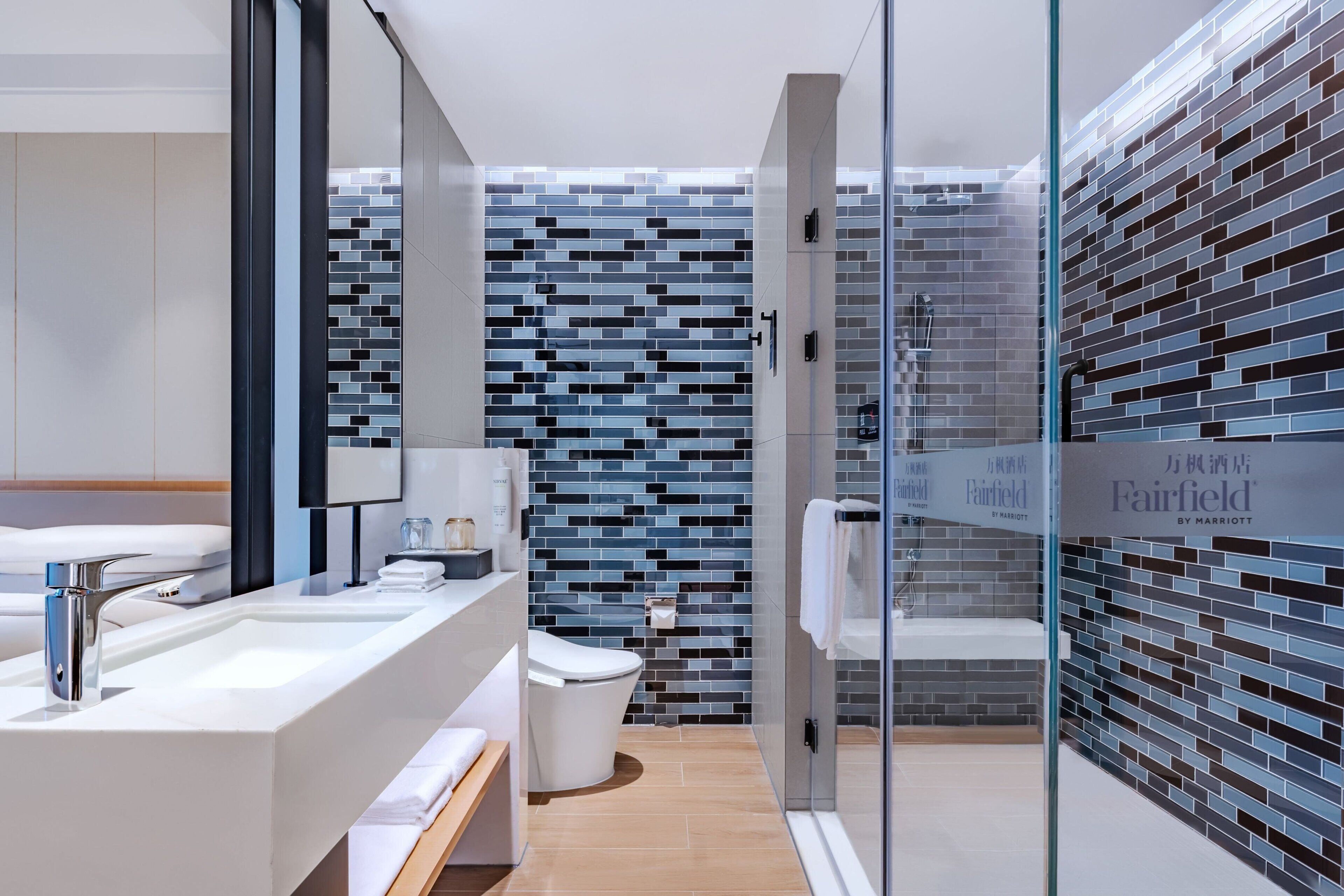 Un baño moderno con cabina de ducha de vidrio, un lavabo blanco y un inodoro.