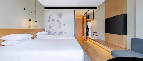 A modern hotel room with a large bed, a seating area, and a TV.