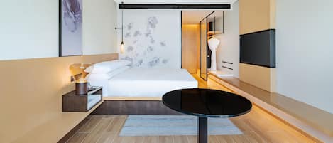 Una camera d'albergo moderna con un letto, un comodino, una lampada e una TV a schermo piatto fissata al muro.