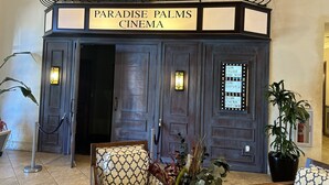 La entrada al cine Paradise Palms, con un diseño clásico, que incluye un cartel luminoso sobre las puertas e iluminación decorativa.