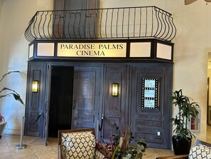 Classic cinema entrance with a decorative awning and potted plants.