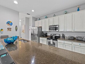 Enjoy cooking in this well-equipped kitchen with a stainless steel refrigerator, microwave, stove, and toaster.