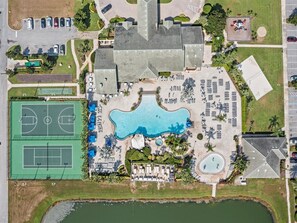 Oversigtsbillede af et resort med en stor swimmingpool, tennisbaner og en strand.