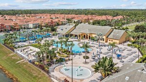 Un resort con varias piscinas, una piscina grande central y una cancha de tenis.