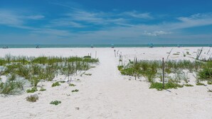 A sandy beach path leading to the ocean with sparse vegetation and a clear sky. - Beach Bungalow- Perfect duplex for larger families (Fort Myers Beach)