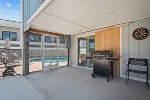 An outdoor patio with a barbecue grill, lounge chairs, and a pool view. - Beach Bungalow- Perfect duplex for larger families (Fort Myers Beach)