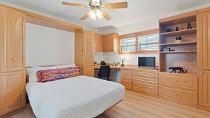 Une chambre à coucher avec un lit, un bureau, une chaise et une armoire.