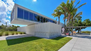 A modern building with a flat roof and large windows, labeled "SIESTA BEACH". - Jamaica Royale #11- Everything NEW, 3 Heated Pools, Right on the Beach! (Siesta Key)