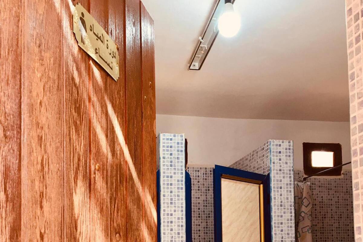 A wooden door with a brass plate, a bathroom with a toilet, and tiled walls.