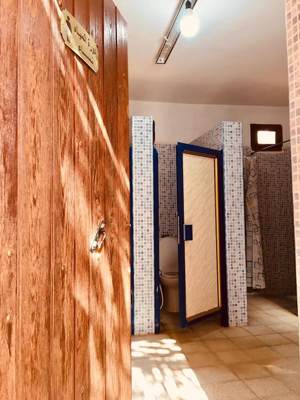 A wooden door with a brass plate, a bathroom with a toilet, and tiled walls.