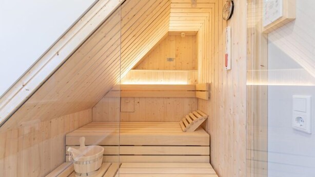 A sauna with wooden benches, a wooden bench with a towel, and a wooden bench with a towel. - Moderne Doppelhaushälfte in Niebüll (Niebüll)