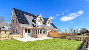 A modern house with a brick exterior, large windows, and solar panels on the roof. - Moderne Doppelhaushälfte in Niebüll (Niebüll)