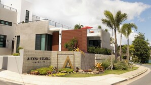 A modern building with a sign reading "ALFAYA ESTATES" and a large 'A' logo. - Luxury home with private pool steps from Black Eagle Beach (Rincón)