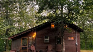 Une cabane rustique avec une véranda, une petite table et un banc.