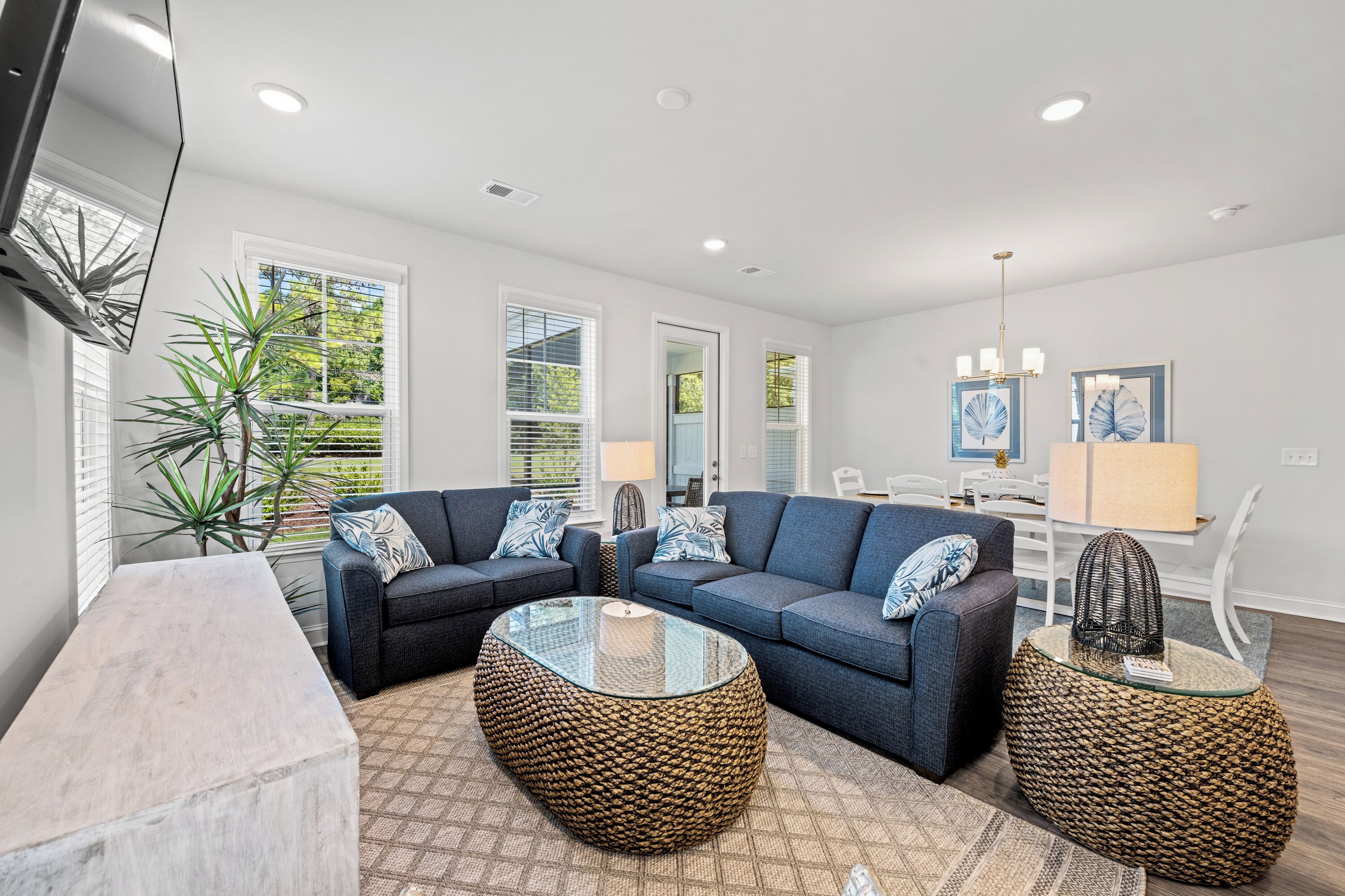 A modern living room with a sectional sofa, a glass coffee table, and a round woven side table.