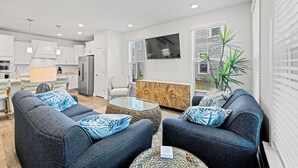A modern living room with grey sofas, a glass coffee table, and a wooden cabinet. - Townes at Barefoot 5122 - Golf, Shopping & Dining (North Myrtle Beach)