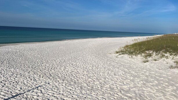 A beach with white sand and clear blue water. - Beautiful Beach Home Steps from the crystal blue waters of Navarre Beach! (Navarre)