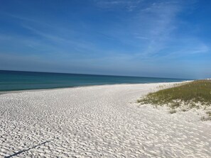 A beach with white sand and clear blue water.
