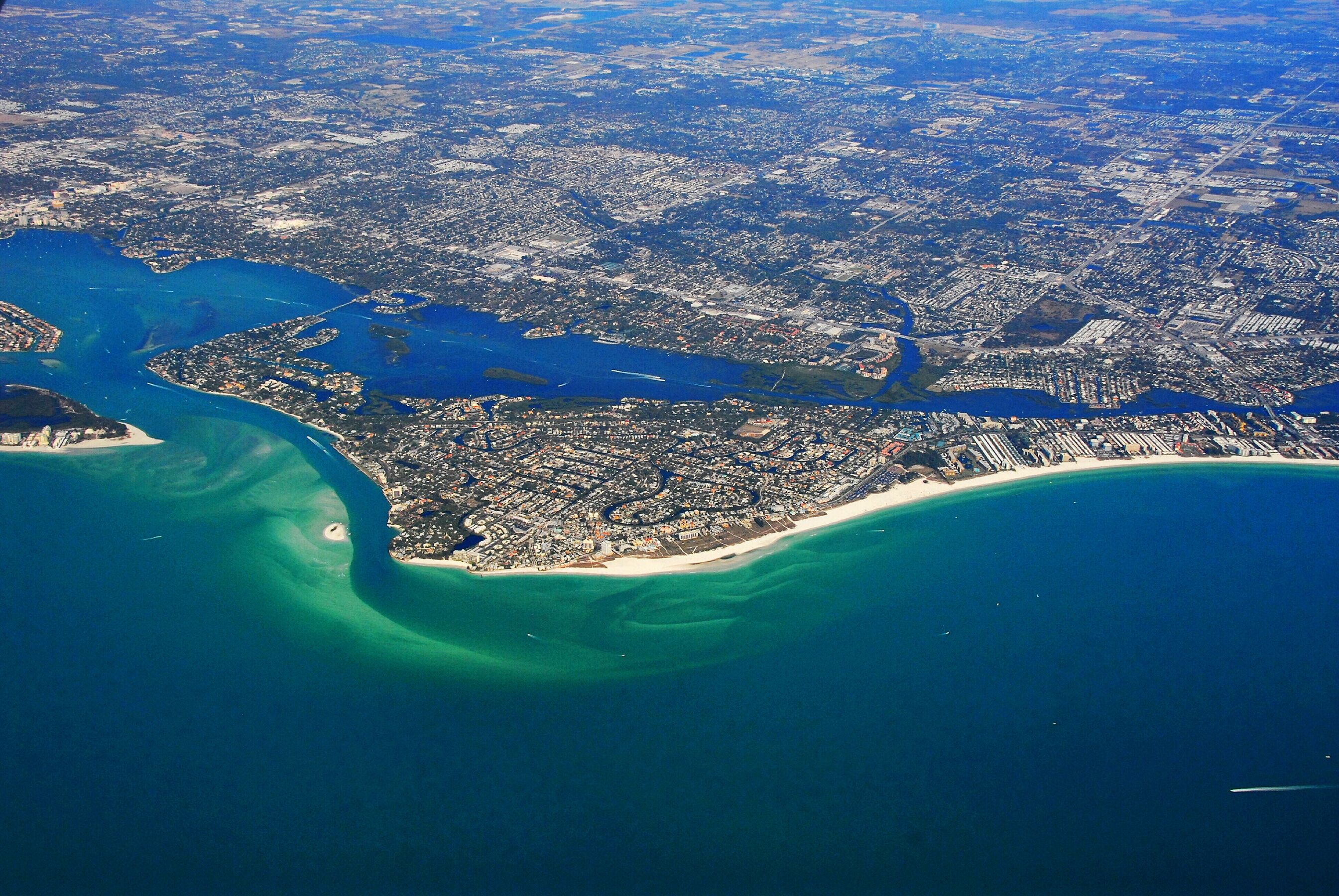 An aerial view of a coastal city with a prominent beach and a large body of water.