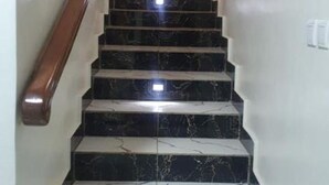 A staircase with black marble steps and a wooden handrail, leading to a landing with a door.