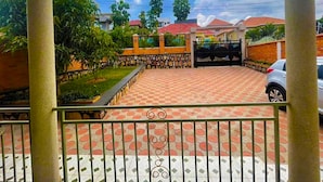 A residential area with a paved driveway, a gated entrance, and a car parked nearby.