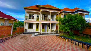 A two-story house with a balcony, a paved driveway, and a garden area.