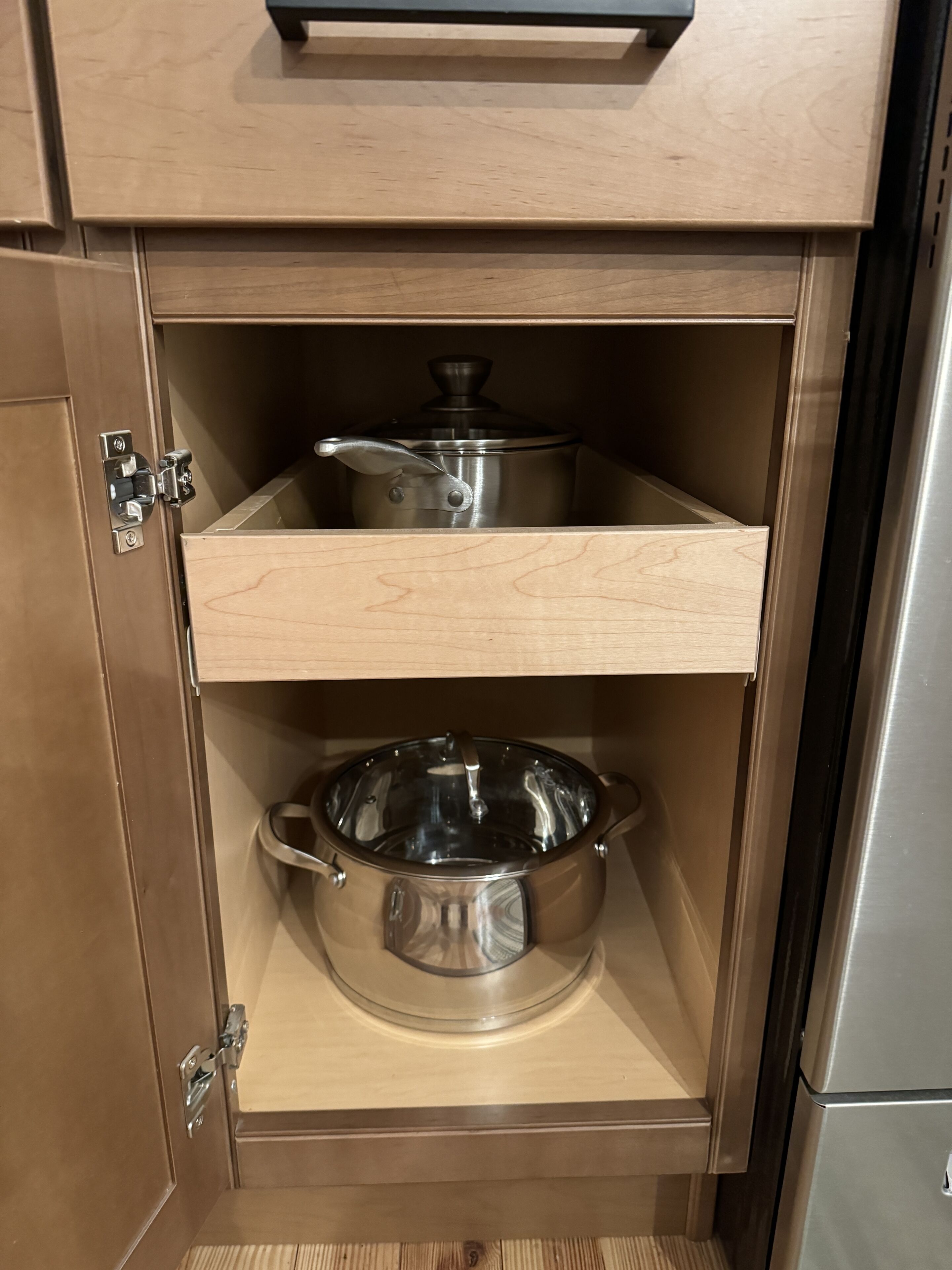 Un meuble de cuisine contenant deux casseroles en acier inoxydable et un couvercle en verre.