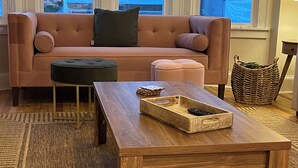 A living room with a sofa, ottoman, and coffee table.