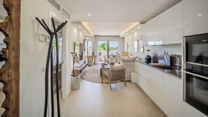 A modern kitchen with white cabinetry, a built-in oven, and a large window.