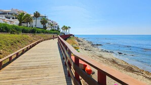 A wooden boardwalk leading to a beach with a clear view of the ocean.
