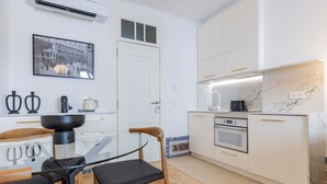 Una cocina moderna con armarios blancos, una mesa de comedor de vidrio y una silla negra.