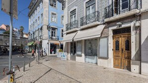 A street with cobblestone pavement, a yellow bicycle, and a building with a wooden door and a balcony. - Figueira Quality III by LovelyStay (Lisboa)