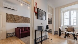 A modern living room with a red sofa, a glass coffee table, and a dining area with a wooden table and chairs. - Figueira Quality III by LovelyStay (Lisboa)