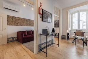 Un salon moderne avec un canapé rouge, une table basse en verre et un coin repas comprenant une table et des chaises en bois.