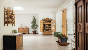 A spacious room with a large wooden cabinet, a potted plant, and a bookshelf.