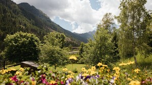 A mountain landscape with a wooden cabin and a field of flowers in the foreground.