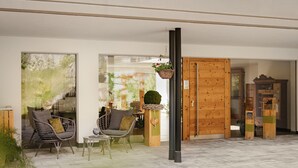 A spacious room with a large window, wicker chairs, a small table, and a wooden cabinet.