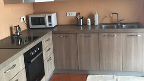 Une cuisine moderne avec des meubles de couleur bois clair, un four à micro-ondes, une cuisinière et un évier.