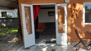 Ein Holzhaus mit offener Tür, die auf eine Terrasse führt.