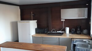 Eine kleine Küche mit Kühlschrank, Mikrowelle und Kaffeemaschine.