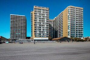 A high-rise building with multiple balconies and a flat rooftop area.