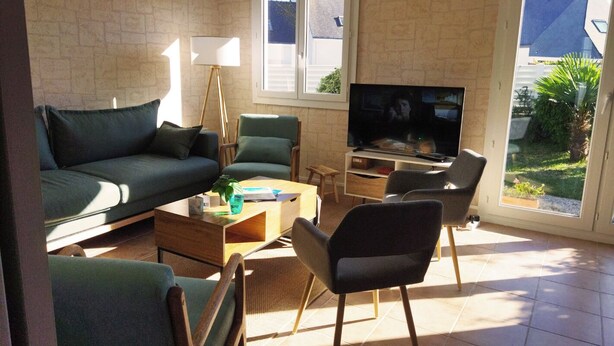 Ein Wohnzimmer mit einer Couch, Sesseln, einem Couchtisch, einem Fernseher und einem Fenster mit Aussicht.