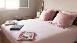 Ein Schlafzimmer mit einem großen Bett, einem Nachttisch mit Lampe und einem Fenster mit Jalousien.