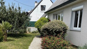 Ein Wohnhaus mit Kiesweg, gepflegtem Rasen und verschiedenen Sträuchern und Blumen.