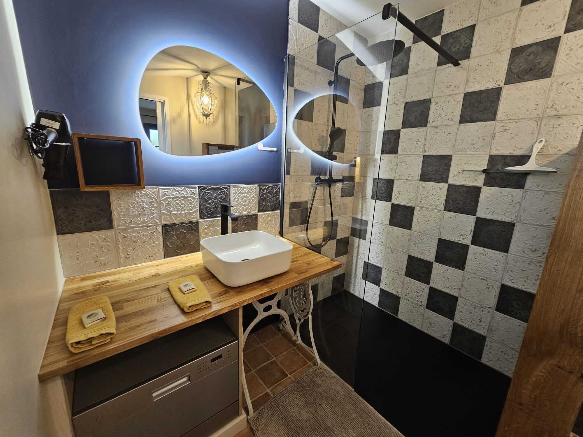 A modern bathroom with a wooden vanity, a sink, and a shower with checkered tiles.