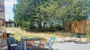 An outdoor patio with a table and chairs, surrounded by a wooden fence and trees. - Chambre de Charme, Gîte de L'archerie (Saint-Lambert-la-Potherie)